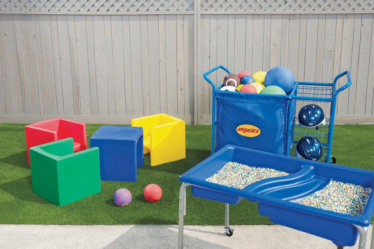 Children's Factory Children's Cube Chairs - 4 Primary Colors, colorful plastic cube chairs in red, blue, green, and yellow arranged outdoors on artificial grass.